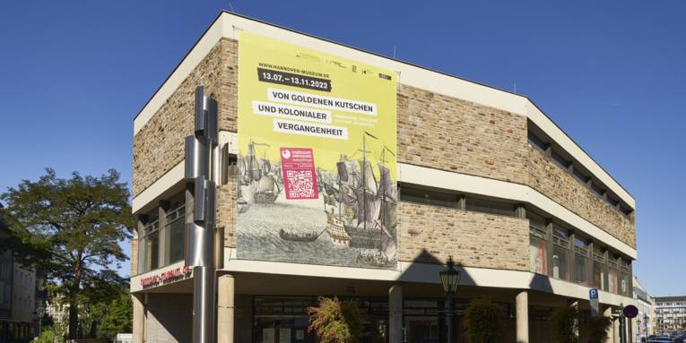 Haupteingang des Historischen Museums mit Ausstellungsbanner "Von goldenen Kutschen und kolonialer Vergangenheit. Hannover, England und die Sklaverei"